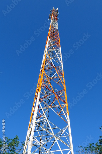 Red and white cell phone mast, radio communication station against bright blue sky, Alter do Chao, state of Pará, Brazil.