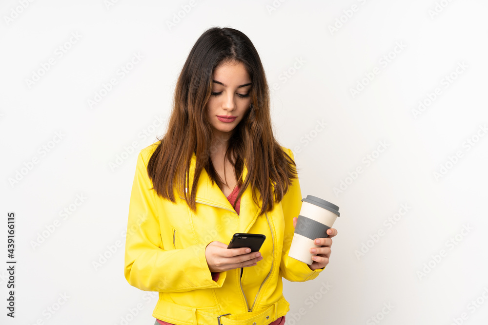 Young caucasian woman isolated on white background holding coffee to take away and a mobile Young caucasian woman isolated on white background holding coffee to take away and a mobile