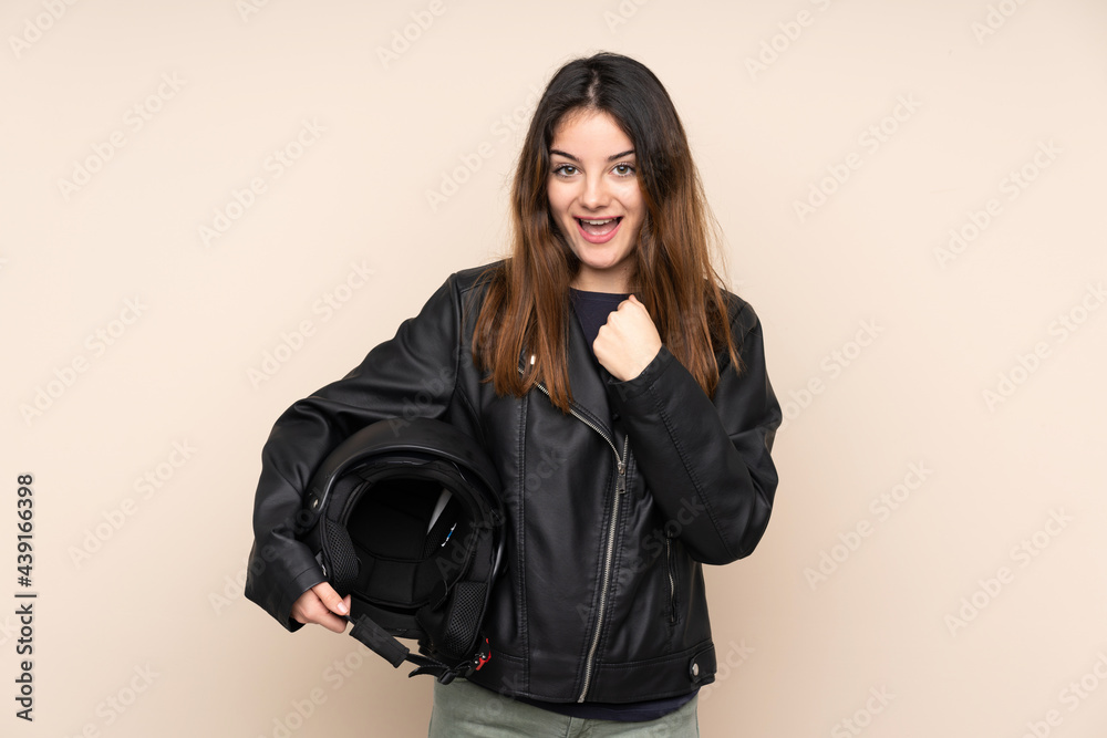 Woman with a motorcycle helmet isolated on beige background celebrating a victory