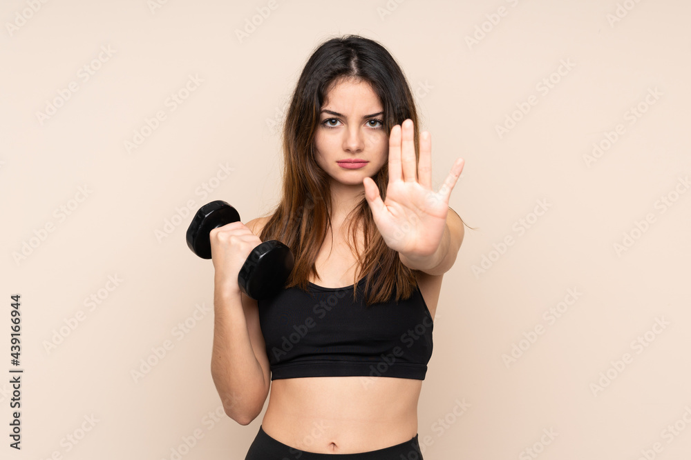 Young sport woman making weightlifting isolated on beige background making stop gesture with her hand Young sport woman making weightlifting isolated on beige background making stop gesture with her hand
