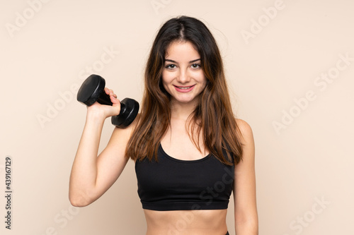 Young sport woman making weightlifting isolated on beige background