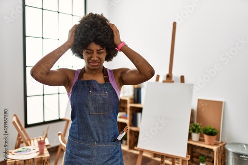 Obraz na plátně Young african american woman with afro hair at art studio suffering from headache desperate and stressed because pain and migraine