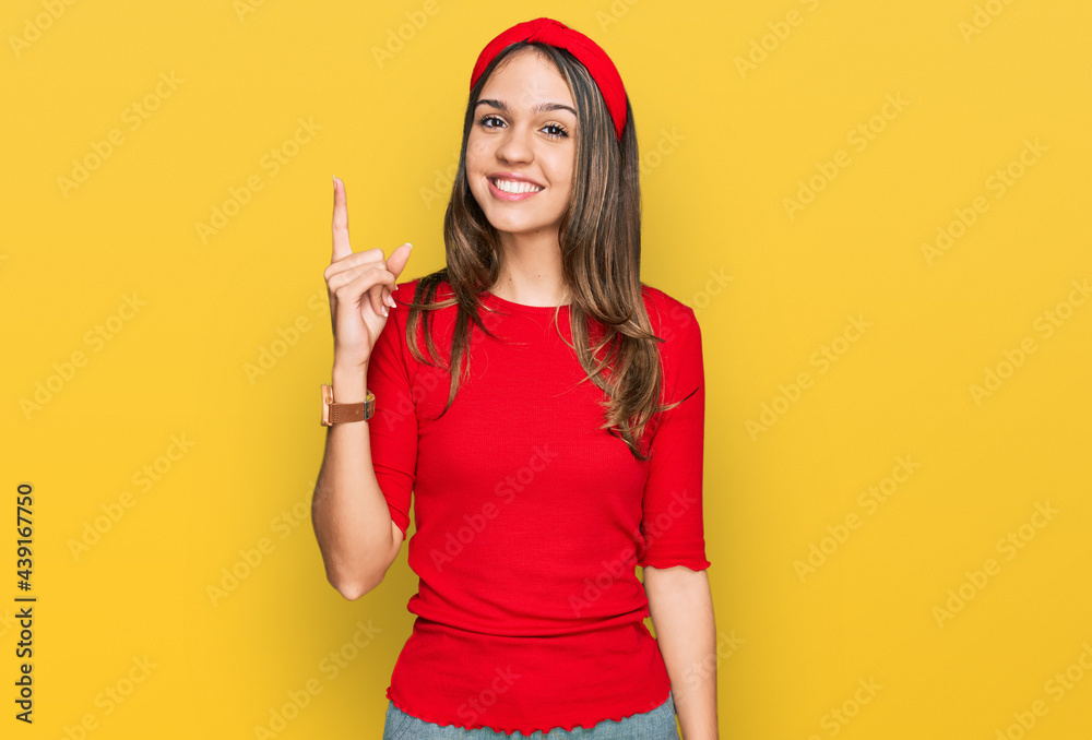 Young brunette woman wearing casual clothes showing and pointing up with finger number one while smiling confident and happy. Young brunette woman wearing casual clothes showing and pointing up with finger number one while smiling confident and happy.
