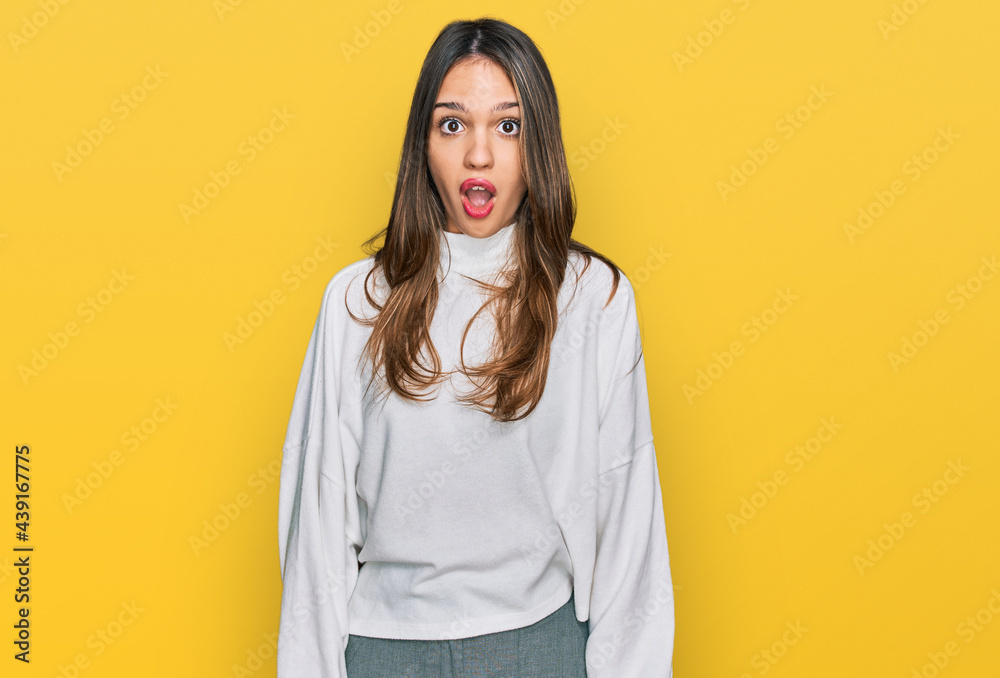 Young brunette woman wearing casual turtleneck sweater afraid and shocked with surprise expression, fear and excited face. Young brunette woman wearing casual turtleneck sweater afraid and shocked with surprise expression, fear and excited face.