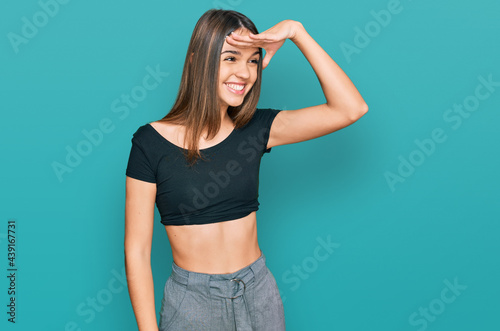 Young brunette woman wearing casual clothes very happy and smiling looking far away with hand over head. searching concept. © Krakenimages.com