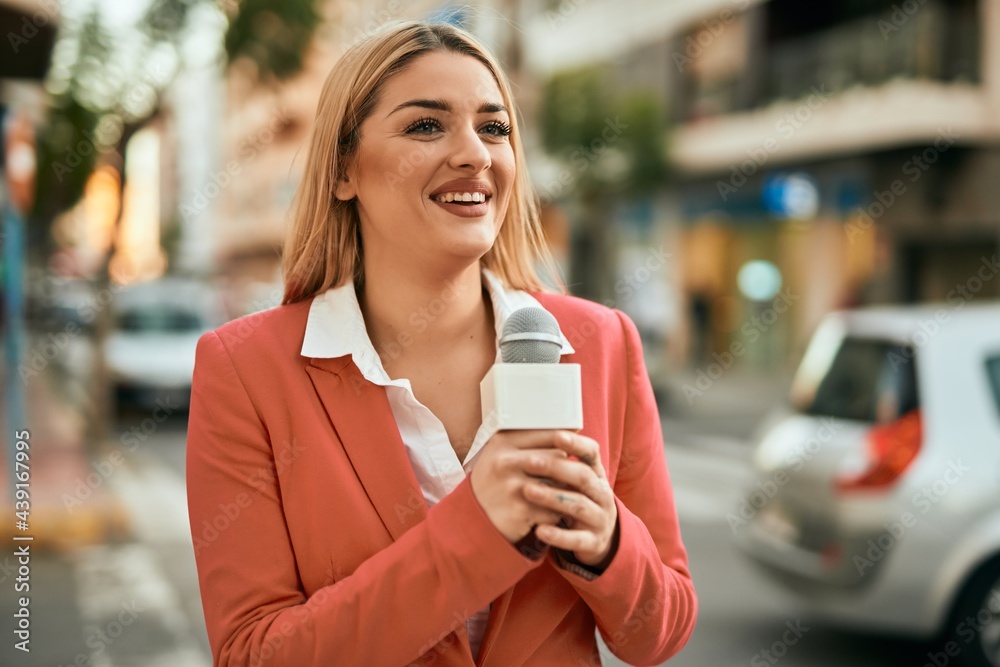 Young blonde reporter woman working using microphone at the city. Young blonde reporter woman working using microphone at the city.