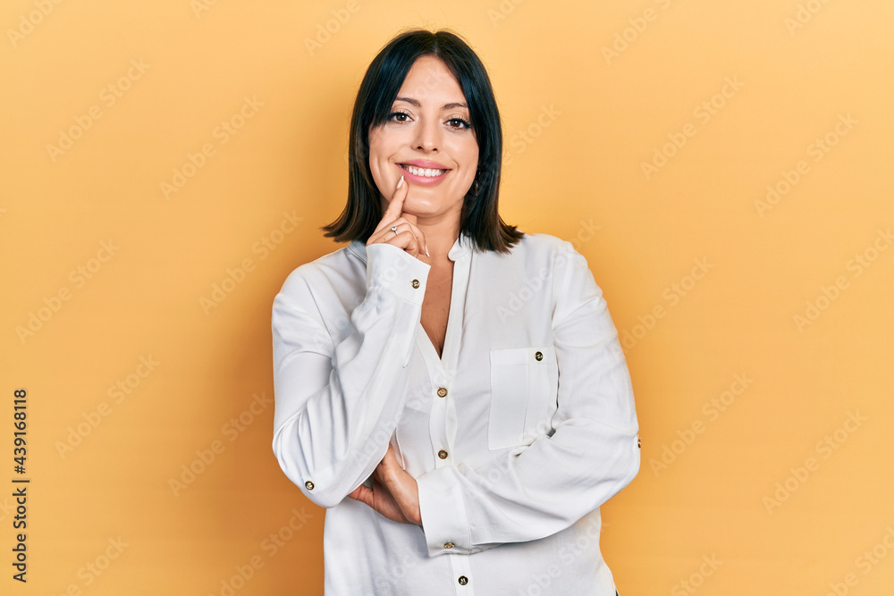 Young hispanic woman wearing casual clothes looking confident at the camera with smile with crossed arms and hand raised on chin. thinking positive.
