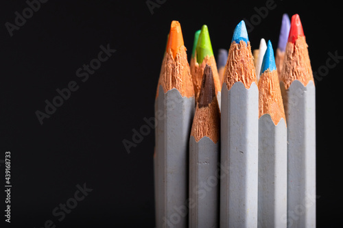 Closeup bunch of color pencils in used and old condition on black background