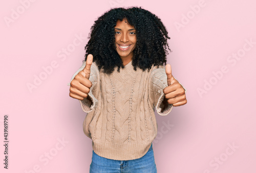 Young african american girl wearing casual clothes approving doing positive gesture with hand, thumbs up smiling and happy for success. winner gesture.