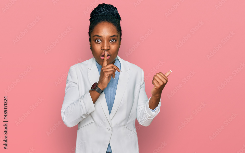 Young african american woman wearing business clothes asking to be quiet with finger on lips pointing with hand to the side. silence and secret concept. Young african american woman wearing business clothes asking to be quiet with finger on lips pointing with hand to the side. silence and secret concept.