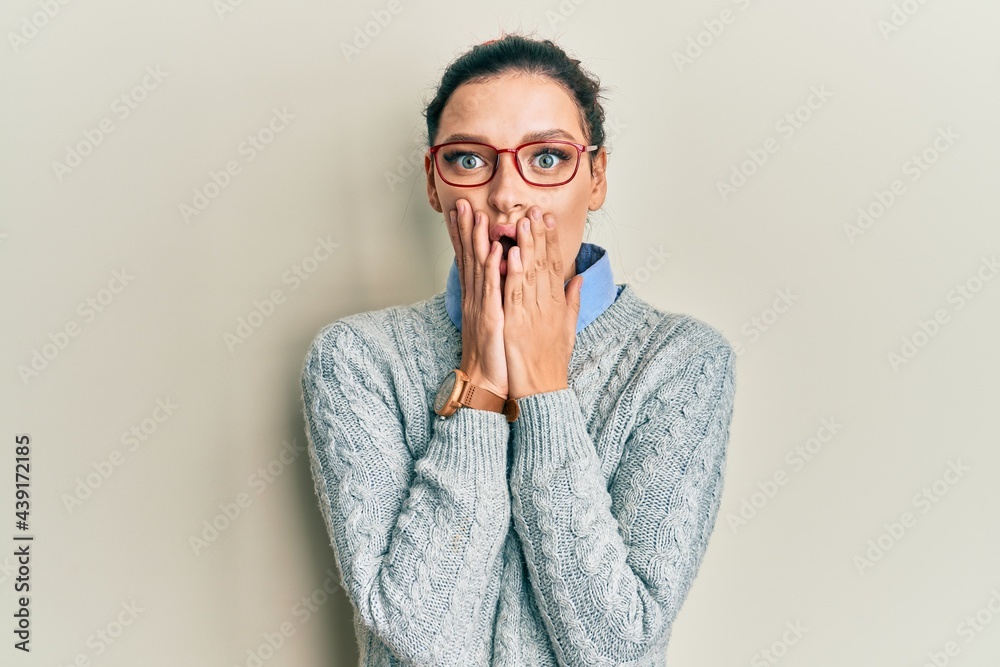 Young caucasian woman wearing casual clothes and glasses afraid and shocked, surprise and amazed expression with hands on face Young caucasian woman wearing casual clothes and glasses afraid and shocked, surprise and amazed expression with hands on face