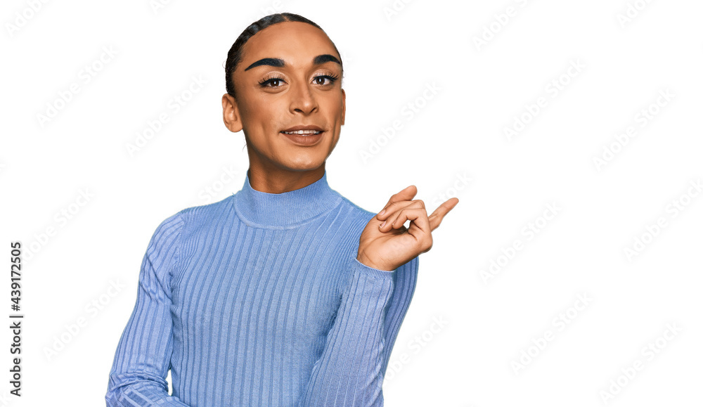 Hispanic transgender man wearing make up and long hair wearing casual clothes smiling happy pointing with hand and finger to the side Hispanic transgender man wearing make up and long hair wearing casual clothes smiling happy pointing with hand and finger to the side