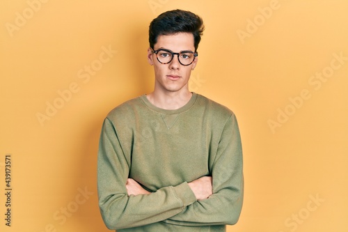 Young hispanic man with arms crossed gesture relaxed with serious expression on face. simple and natural looking at the camera.