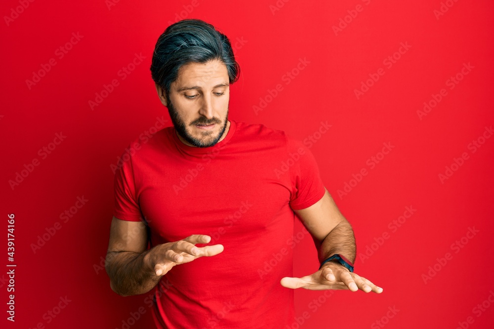 Fototapeta premium Young hispanic man wearing casual red t shirt disgusted expression, displeased and fearful doing disgust face because aversion reaction.