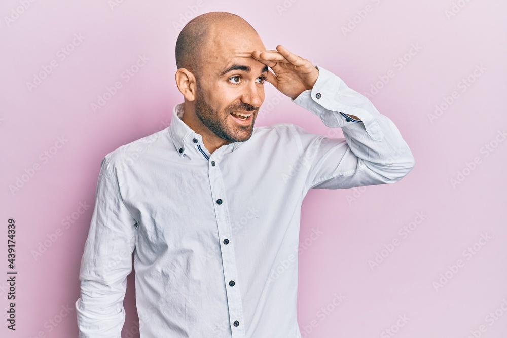 Young hispanic man wearing casual clothes very happy and smiling looking far away with hand over head. searching concept. Young hispanic man wearing casual clothes very happy and smiling looking far away with hand over head. searching concept.