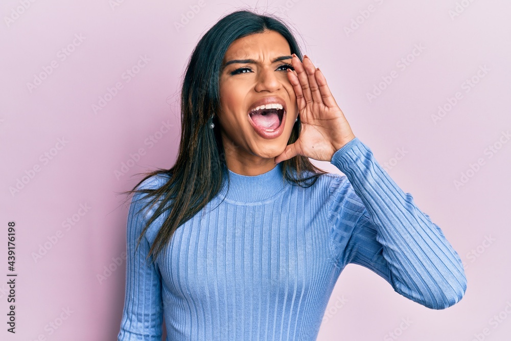 Young latin transsexual transgender woman wearing casual clothes shouting and screaming loud to side with hand on mouth. communication concept. Young latin transsexual transgender woman wearing casual clothes shouting and screaming loud to side with hand on mouth. communication concept.
