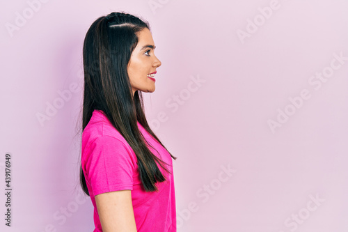 Young hispanic girl wearing casual pink t shirt looking to side, relax profile pose with natural face and confident smile.