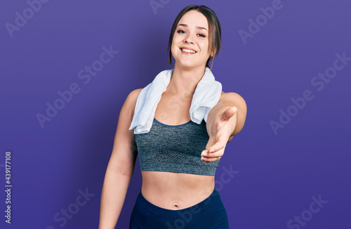 Young hispanic girl wearing sportswear and towel smiling cheerful offering palm hand giving assistance and acceptance.