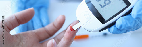 Doctor measuring patients blood glucose with glucometer closeup photo