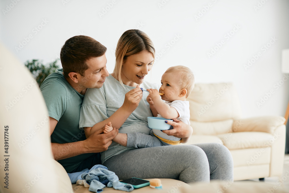 Young caring parents feeding their small son with baby food. Young mother and father feeding their baby boy with solid food at home. Young caring parents feeding their small son with baby food. Young mother and father feeding their baby boy with solid food at home.
