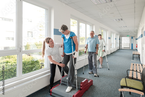 Seniors in rehabilitation learning how to walk with crutches photo