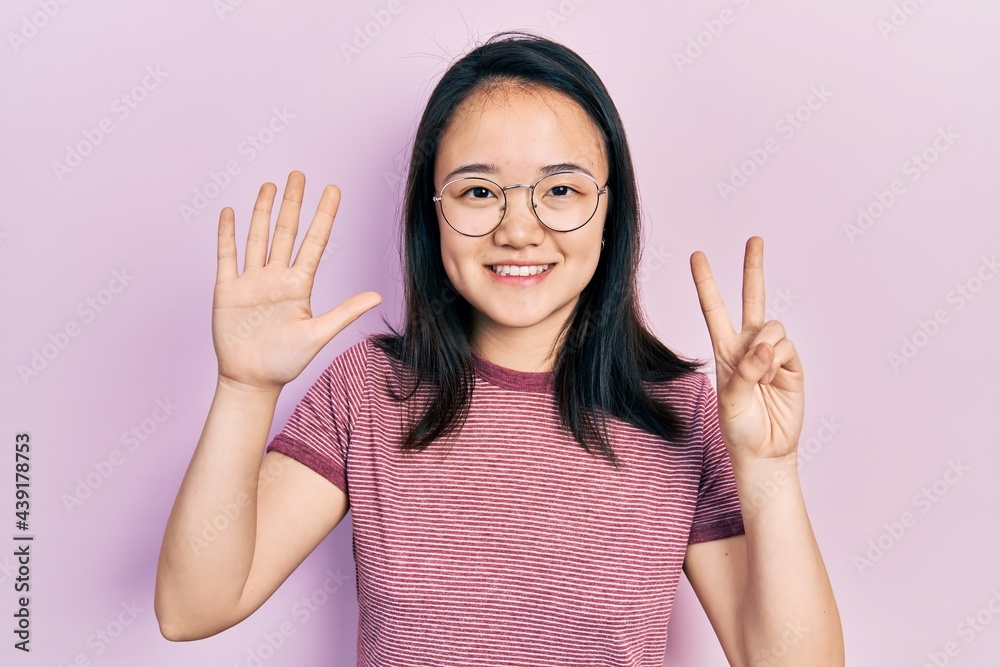 Young chinese girl wearing casual clothes and glasses showing and pointing up with fingers number seven while smiling confident and happy. Young chinese girl wearing casual clothes and glasses showing and pointing up with fingers number seven while smiling confident and happy.