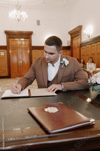 the groom signs the marriage documents photo