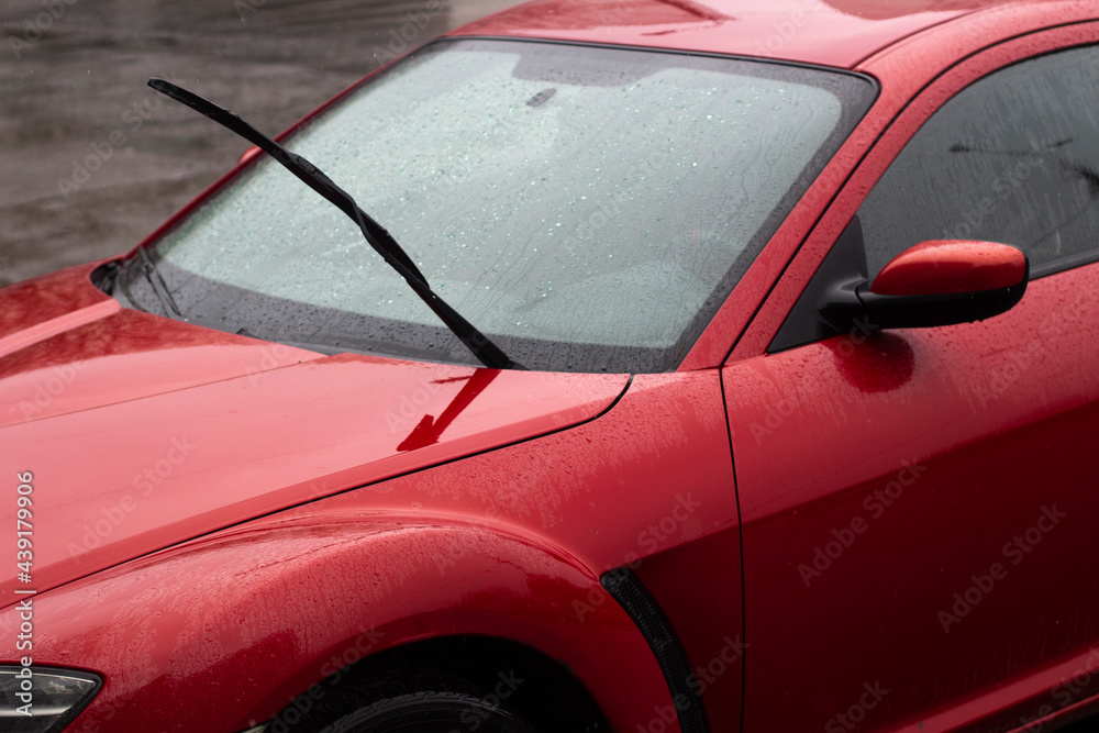 Red car in the parking lot. Car surface. Wet car after rain.