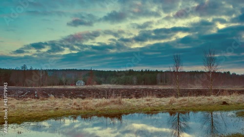 4k time lapse with spring landscape. Lonely house near forest under cloudy sky. photo