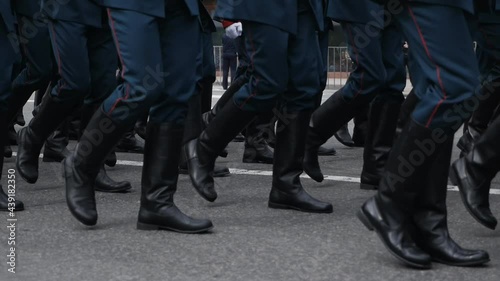Close-up of the feet of military personnel marching in a parade in slow motion. Military march. Blue uniform. clothes and black boots
