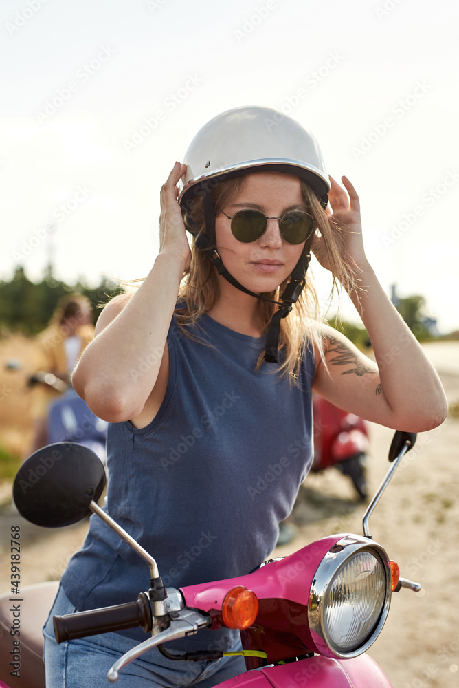 Fototapeta premium Happy young caucasian girl sitting on retro scooter