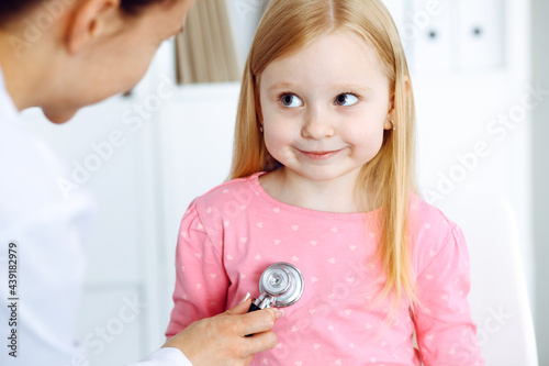 Happy smiling female kid-patient at usual medical inspection. Doctor and young girl in the clinic. Medicine, healthcare concepts