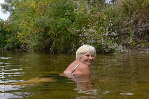 Fototapeta Naklejka Na Ścianę i Meble -  Woman is posing in the river water in cloudy day.