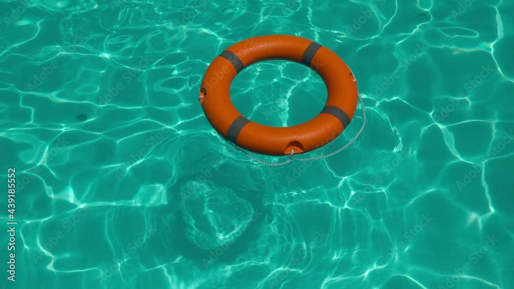 high angle view of an orange lifebuoy floating on clear water - life-saving and rescue concept high angle view of an orange lifebuoy floating on clear water - life-saving and rescue concept