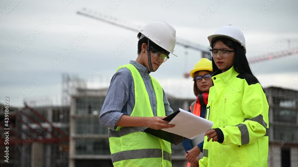 Young and senior Engineers discuss about work of large building underconstruction,Three people working on site of under construction Young and senior Engineers discuss about work of large building underconstruction,Three people working on site of under construction