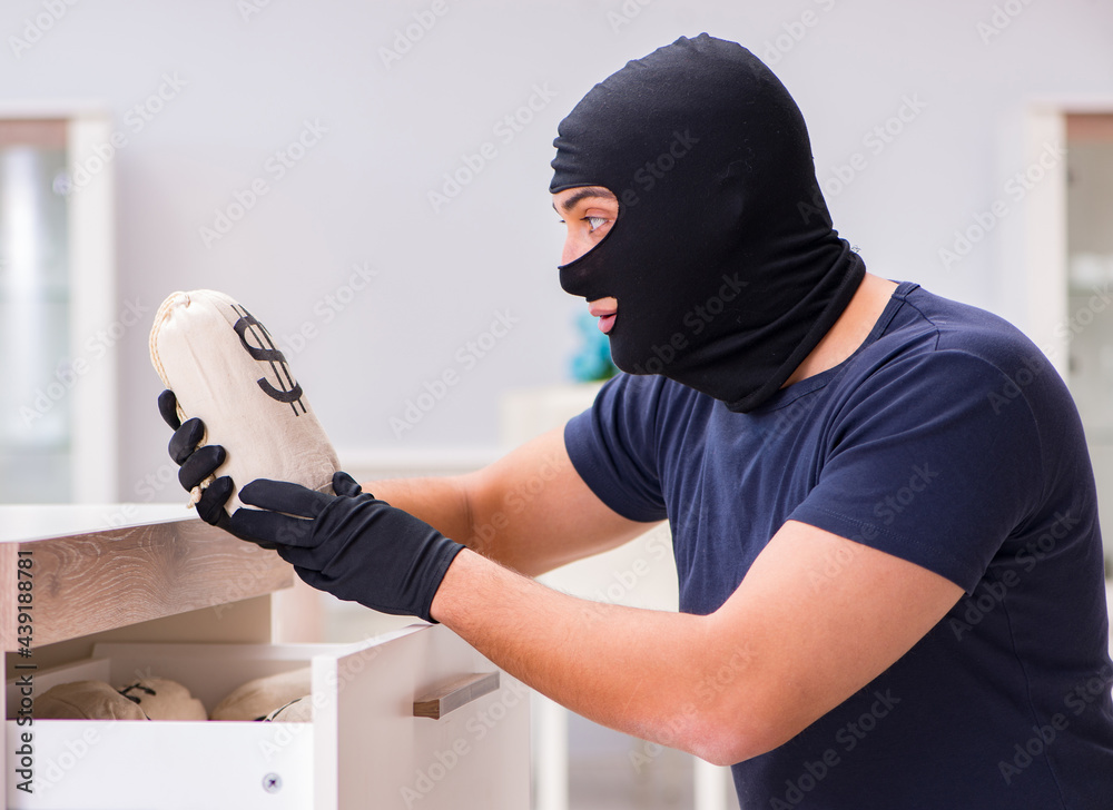 Robber wearing balaclava stealing valuable things Robber wearing balaclava stealing valuable things