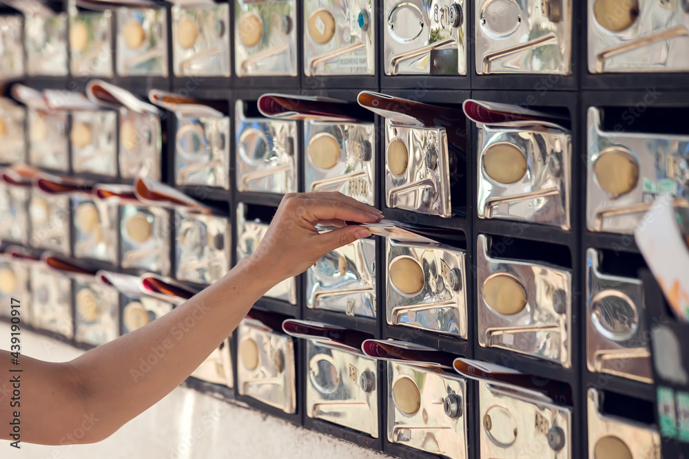 Mailboxes with newspaper inside. Woman taking away the correspondence. News and delivery concept