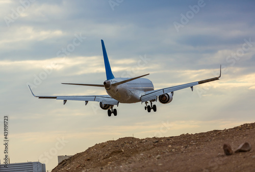 Airplane taking off close-up. Aircraft at sunset over the land. Airliner landing in the desert. White passenger plane on the background of a beautiful sky
