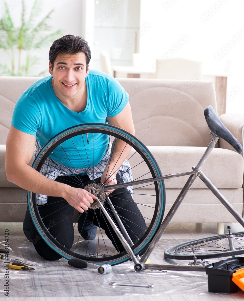 Obraz premium Young man repairing bicycle at home