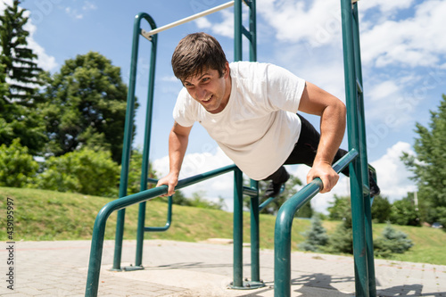 Adult caucasian man training outdoor male doing push ups in sunny day street workout real people concept