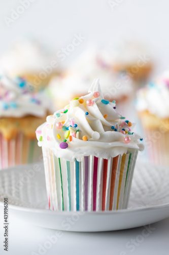 Close up of a confetti cupcake with frosting and other cupcakes in soft focus in behind.