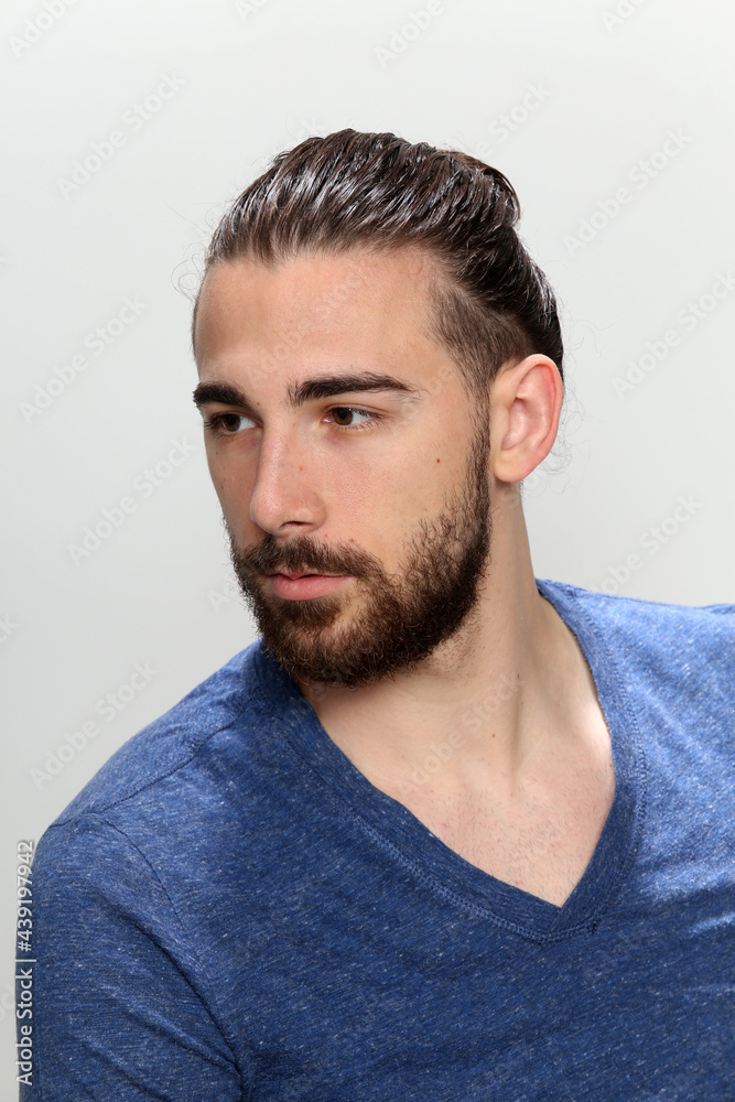 Attractive male model with long hair and beard posing in studio on isolated background. Style, trends, fashion concept. Attractive male model with long hair and beard posing in studio on isolated background. Style, trends, fashion concept.
