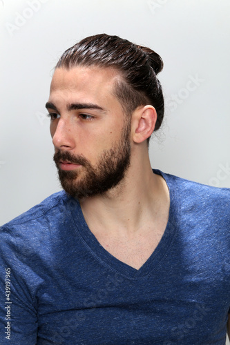 Attractive male model with long hair and beard posing in studio on isolated background. Style, trends, fashion concept. © Bojan
