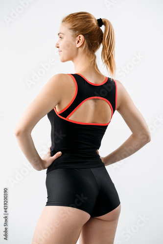 Woman sportswear. Clothing for branding. Fitness outfit. Active lifestyle. Back view of female athlete with slim body in logo mockup black orange tank top shorts isolated on neutral.