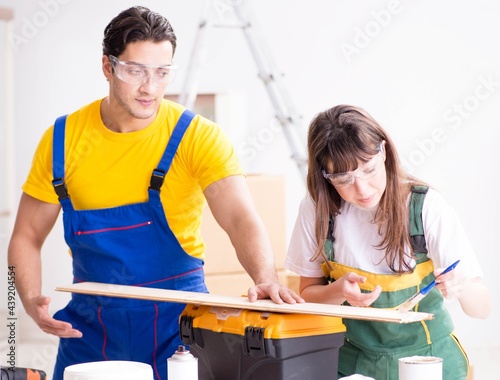 Man explaining woman woodworking tips in wood workshop