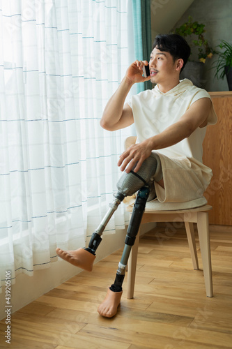 Foto 窓際で電話をする義足をした男性