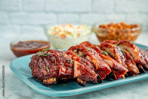Sliced barbeque ribs on blue plate with side dishes