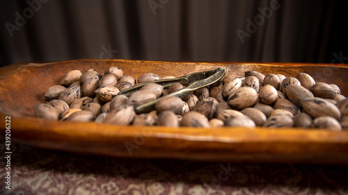 Raw in shell whole Pecan nuts in a wooden bowl on a wood table with a vintage nut cracker