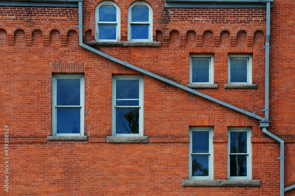 windows and drainpipe of old red brick building