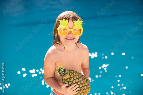 Summer pineapple fruit. Happy child having fun at swimming pool on sunny day. Kids summer holidays and vacation concept.